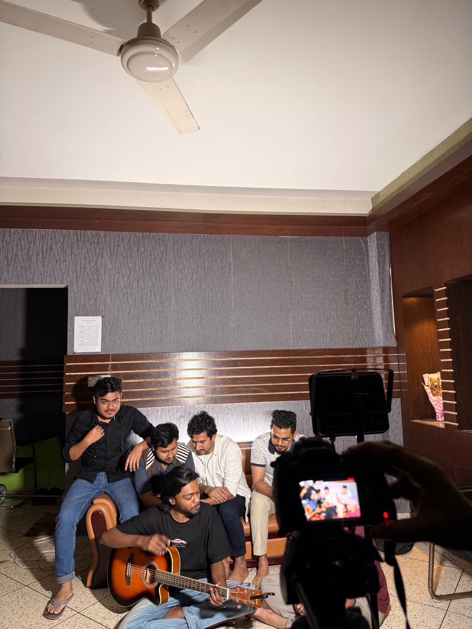 Team filming a group performance with guitar indoors