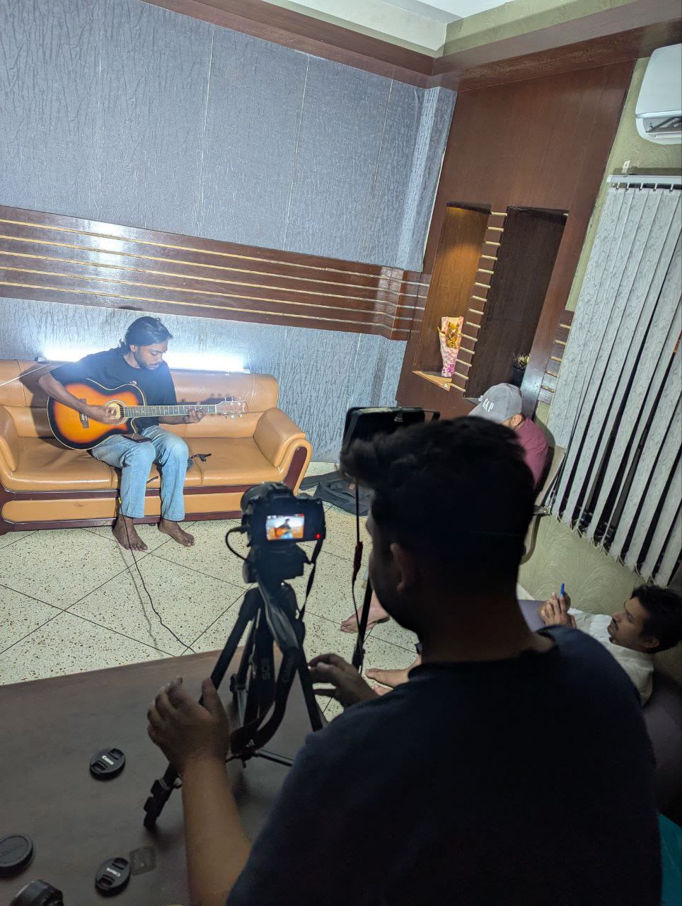 Camera operator filming a guitarist in an indoor studio session