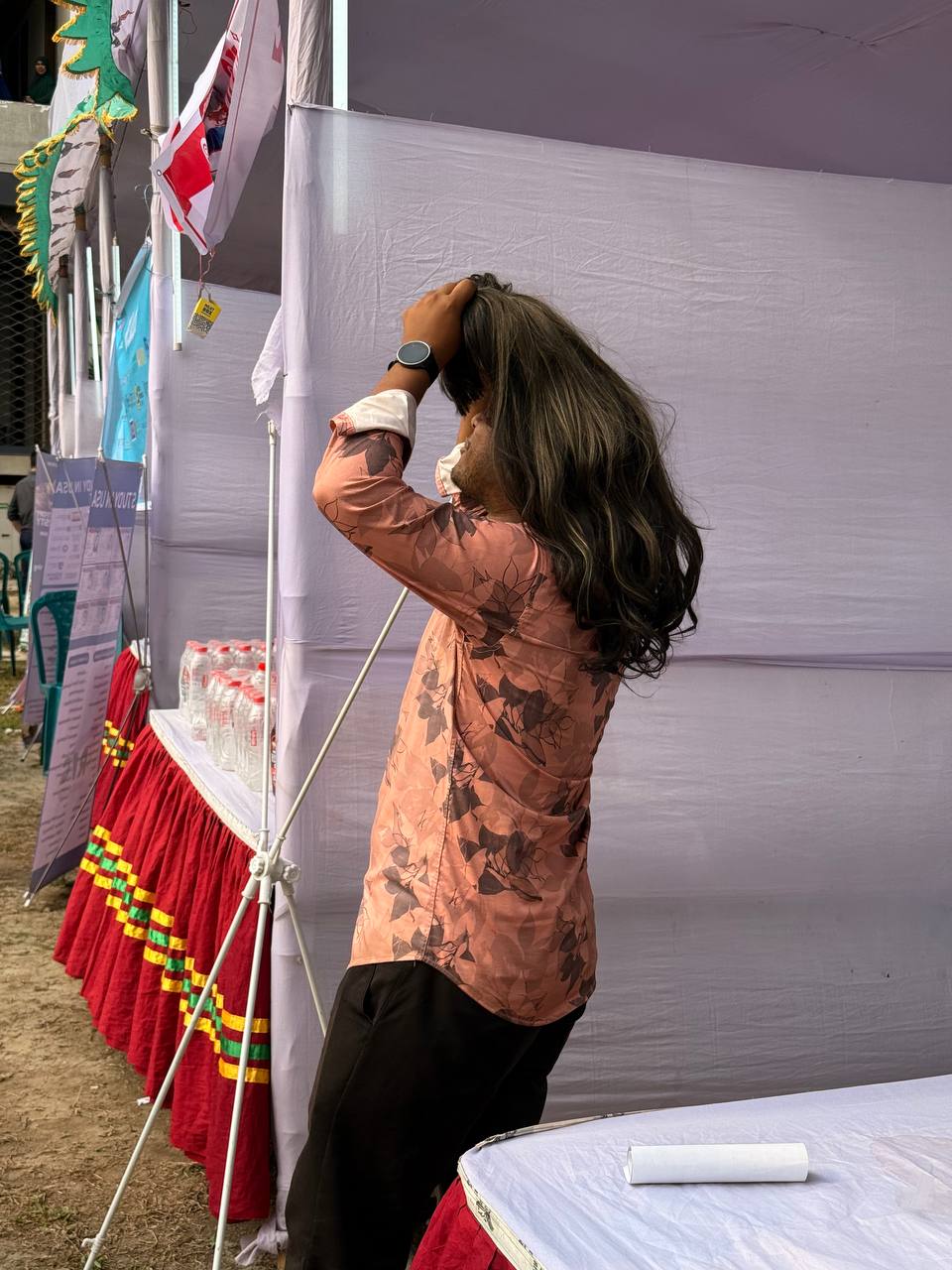 Participant viewing a long hair system beside the event booth