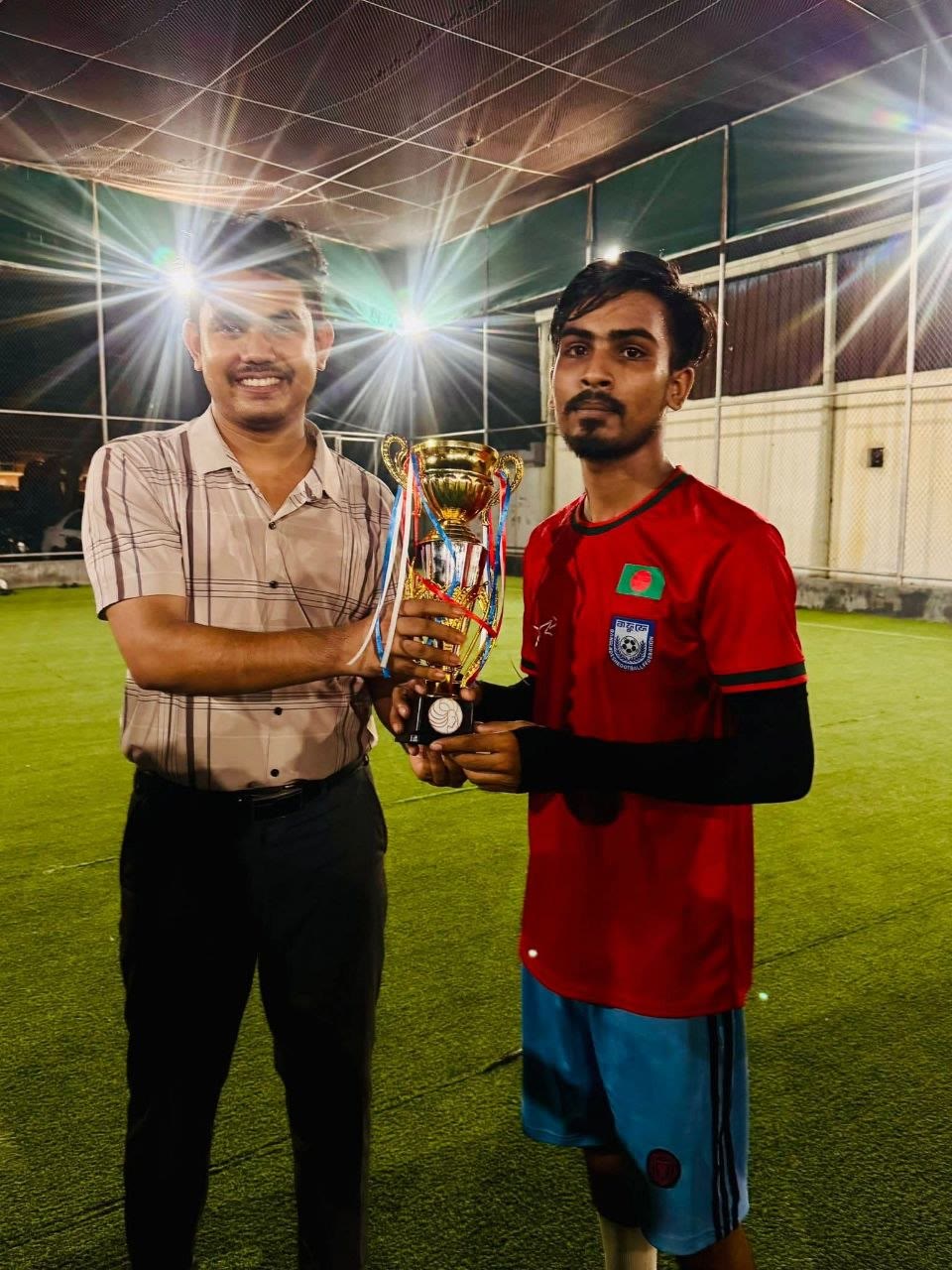 Football player receiving a trophy after the employee match