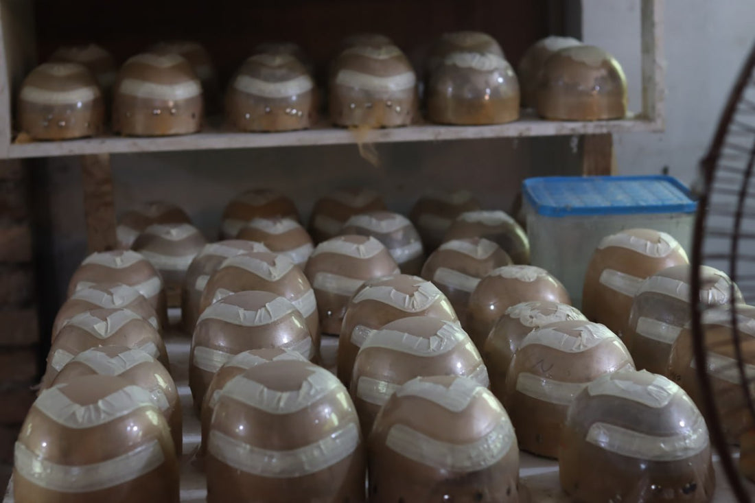 Wholesale human hair wigs for resale displayed on shelves in a workshop.
