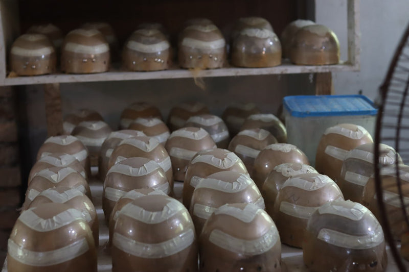 Wholesale human hair wigs for resale displayed on shelves in a workshop.