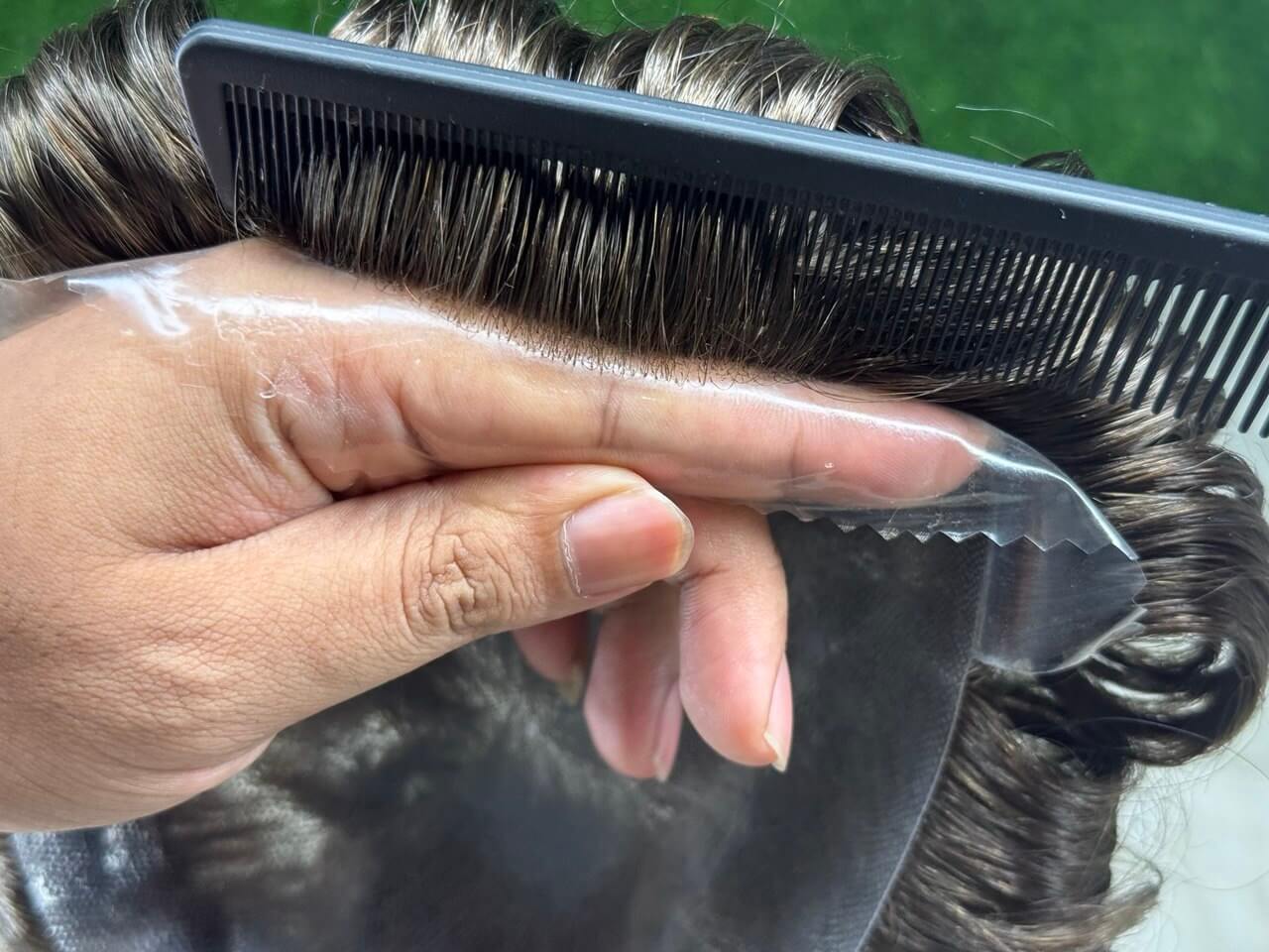 Prótese Capilar Masculina being styled with a comb, showcasing natural hair texture and versatility.