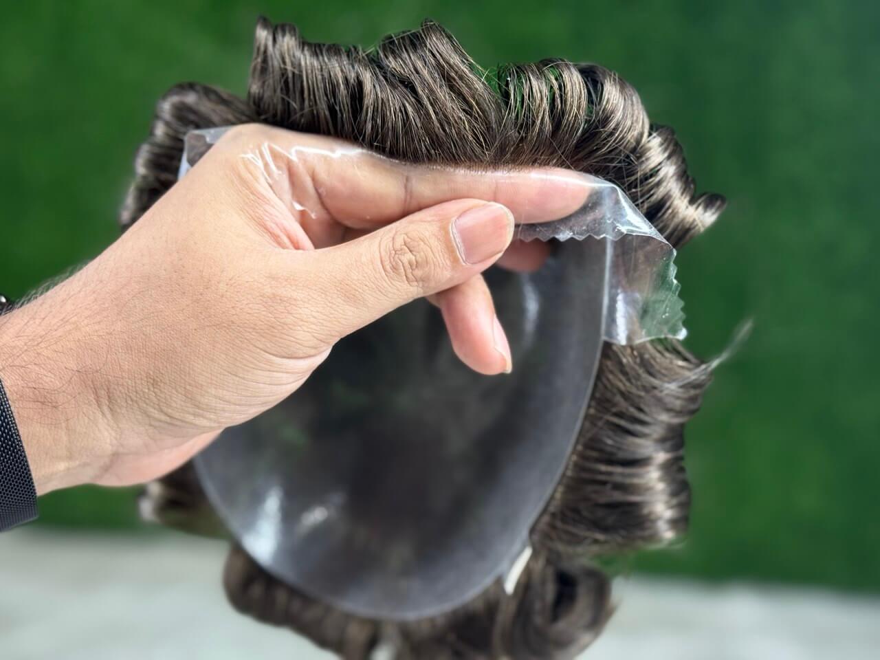 Prótese Capilar Masculina being held, showcasing high-quality human hair and realistic design for men.