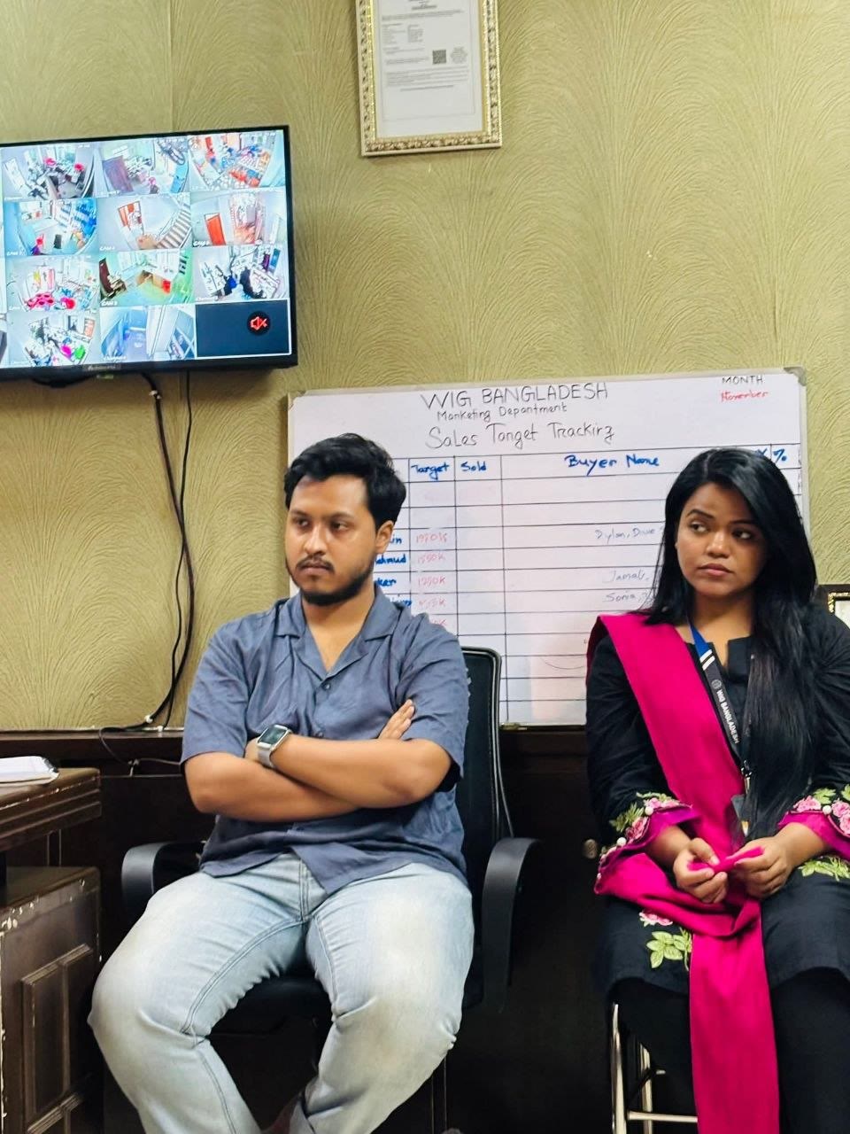 Marketing team members seated beside a sales target tracking board